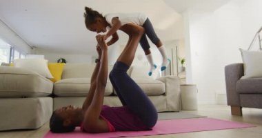 Mutlu Afro-Amerikan anne ve kızı evde yoga egzersizi yapıyor. Karantina süresince evde tek başına kalmak..
