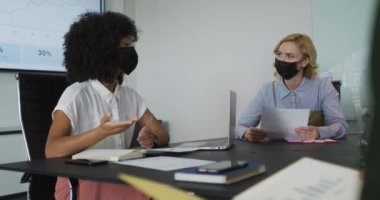 Maske takan Afrikalı Amerikalı bir kadın toplantı odasında sunum yapıyor. Coperid 19 Coronavirus salgını sırasında modern bir ofiste çalışmak..