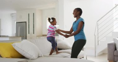 Mutlu Afro-Amerikan anne ve kızı dans ediyor ve evde eğleniyor. Karantina süresince evde tek başına kalmak..