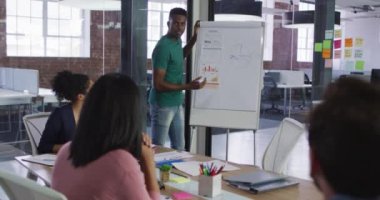 Beyaz yönetim kurulunun yanında duran Afrikalı Amerikalı iş adamı meslektaşlarının önünde sunum yapıyor. bağımsız yaratıcı tasarım işi.