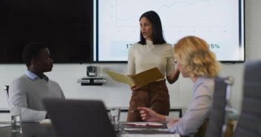 Karışık ırk işkadını toplantı odasında çeşitli meslektaşlarına sunum yapıyor. Modern bir ofiste çalışıyorum..