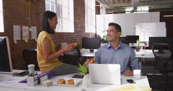 多様な男性と女性のビジネス同僚がペストリーと笑顔を食べています 近代的なオフィスでのビジネス — ストック動画