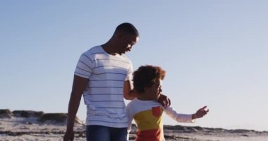 Afrika kökenli Amerikalı baba ve oğul sahilde dikilirken manzaranın tadını çıkarıyorlar. Aile seyahati tatil eğlence konsepti
