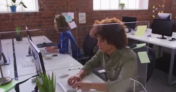 コンピュータを使用してスニーズガード付きの机に座っている多様な男性と女性のビジネス同僚 近代的なオフィスでのビジネス — ストック動画