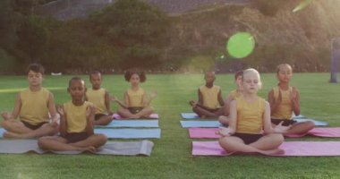 Çeşitli okul çocukları yoga dersleri sırasında minderlerin üzerinde oturup meditasyon yapıyorlar. İlkokuldaki çocuklar yazın.