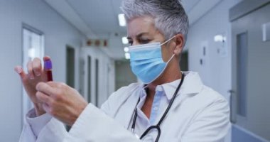 Hastanede elinde kan örneği tutan yüz maskesi takan Kafkas kadın kıdemli doktorun portresi. covid 19 koronavirüs salgını sırasında ilaç, sağlık ve sağlık hizmetleri.