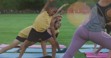 Karışık ırk öğretmeni çeşitli okul çocukları yoga egzersizlerini açık havada gösteriyor. İlkokuldaki çocuklar yazın.