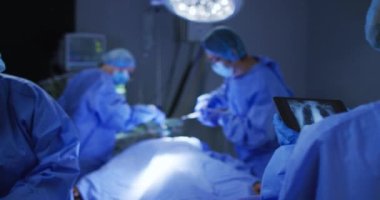 Ameliyat maske takan cerrahlar ameliyathanede tabletteki röntgenlere bakarlar. covid 19 koronavirüs salgını sırasında ilaç, sağlık ve sağlık hizmetleri.