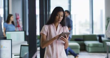 Ofiste tablet kullanan ve kameraya gülümseyen melez iş kadınının portresi. Modern bir ofiste bağımsız yaratıcı iş.