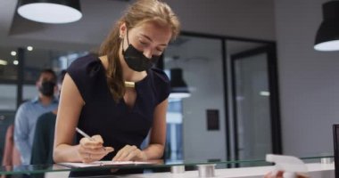 Yüz maskeli beyaz kadının elleri ofis resepsiyonundaki erkek meslektaşları tarafından dezenfekte edilmiş. Coronavirus covid 19 salgını sırasında modern bir ofiste bağımsız bir iş..