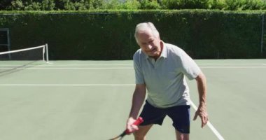 Tenis kortunda raket gölgesi olan beyaz bir adam tenis oynuyor. emeklilik sporları ve aktif yaşlı yaşam tarzı.