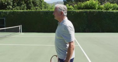 Güneşli bir günde tenis kortunda tenis raketi tutan kıdemli beyaz adamın portresi. emeklilik, altın yıllar ve kıdemli aktif yaşam tarzı.