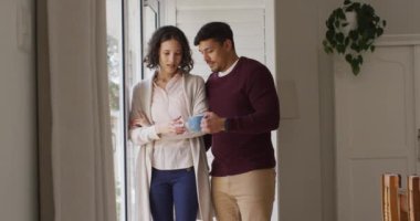 Pencerede dikilen ve kahve içen mutlu İspanyol çift. Karantina süresince evde tecrit altında..