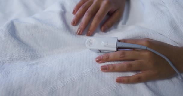 指先パルス酸素濃度計を装着したベッドに寝そべっている混合レース女性患者 医療サービス — ストック動画