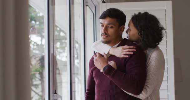 ロマンチックなヒスパニック系のカップルが窓の中に立って抱っこを受け入れる 隔離中に隔離された家で — ストック動画