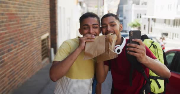 Caddede Yemek Yiyen Selfie Çeken Iki Mutlu Melez Arkadaş Sırt — Stok video