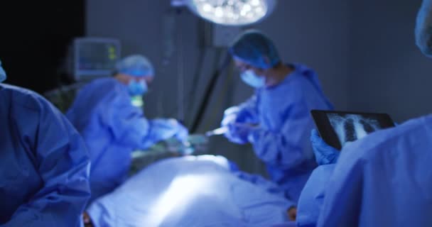 Kirurger Som Bär Ansiktsmasker Opererar Och Tittar Röntgen Surfplattan Operationssalen — Stockvideo