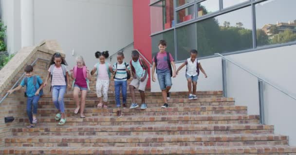 バックパックを身に着けている小学生の多様なグループは 笑顔と学校の後に階下を実行しています 夏の小学校の子どもたちは — ストック動画