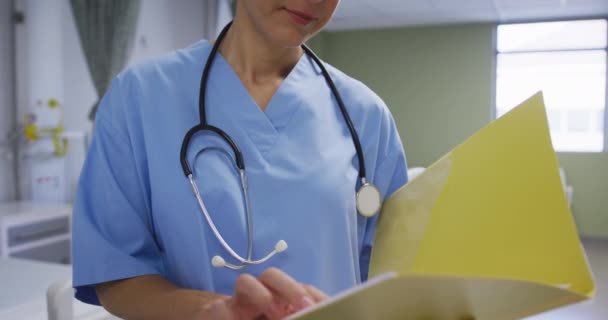 病院の部屋でカメラに笑顔を浮かべて 医療文書を保持白人女性医師 医療サービス — ストック動画