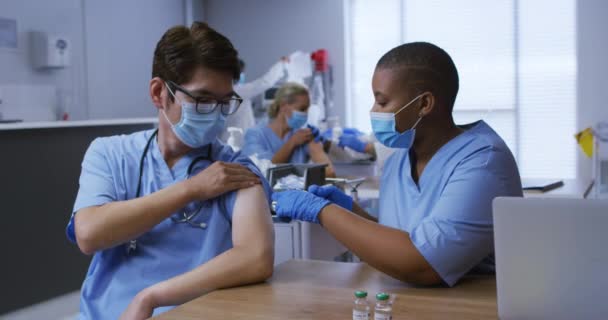 Médico Afroamericano Que Vacuna Covid Colega Asiático Ambos Máscaras Faciales — Vídeo de stock