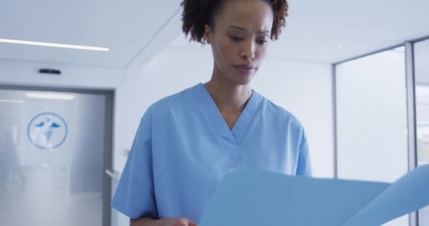 快乐的混血女医务人员站在医院走廊看文件 保健和保健服务 — 图库视频影像