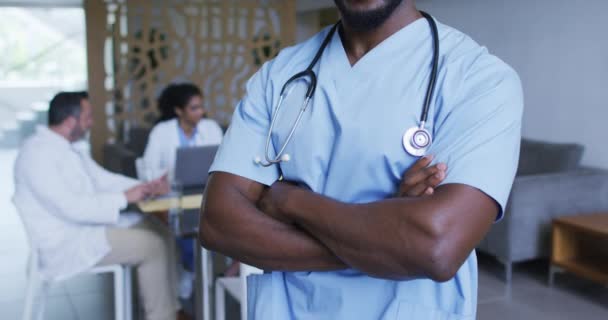 非洲裔美国男医生面带微笑的画像 背景上有同事在讨论 保健和保健服务 — 图库视频影像