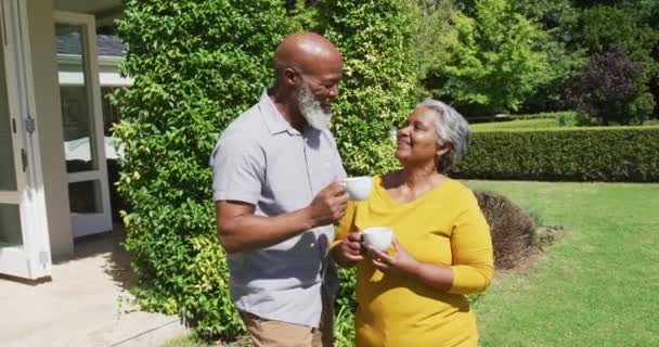 Coppia Afroamericana Anziana Che Parla Tiene Tazze Giardino Soleggiato Pensionamento — Video Stock