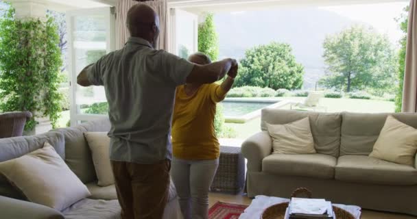自宅のリビングルームでアフリカ系アメリカ人の高齢者のカップルが抱き合っています 定年退職したシニアカップルのライフスタイルのコンセプト — ストック動画