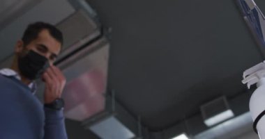 İş adamı yüz maskesi takıyor. İş yerine girerken dezenfekte etmek için dezenfektan kullanıyor. Coronavirus covid 19 salgını sırasında modern bir ofiste bağımsız yaratıcı işler..