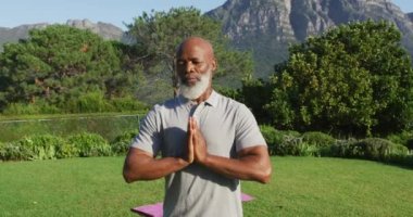 Afrikalı Amerikalı son sınıf öğrencisi bahçede yoga ve meditasyon yapıyor. emeklilik sporları ve aktif yaşlı yaşam tarzı.
