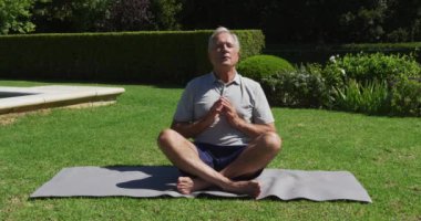Kafkasyalı son sınıf öğrencisi güneşin altında bahçede yoga yapıyor. Karantina süresince evde tecrit altında..