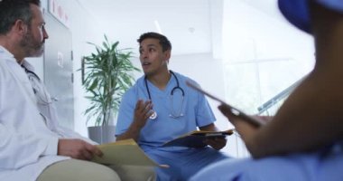 Karışık ırk erkek doktoru hastane personeli toplantısında çeşitli meslektaşlarıyla oturup tartışıyor. ilaç, sağlık ve sağlık hizmetleri.