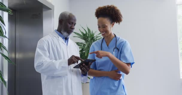 不同的女医生和男医生站在医院里讨论平板电脑的问题 保健和保健服务 — 图库视频影像