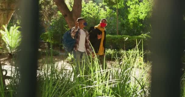 Mutlu Melez Erkek Arkadaş Parkta Yürüyüp Sırt Çantalarıyla Konuşuyor Coronavirus — Stok video