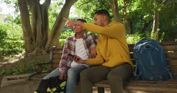 Mutlu Melez Erkek Arkadaş Parkta Sırt Çantalı Akıllı Telefon Kullanıyor — Stok video