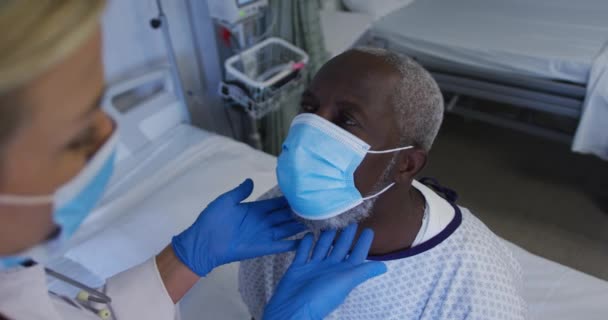 Белая Женщина Врач Осматривает Горло Африканского Пожилого Больного Мужчины Маске — стоковое видео