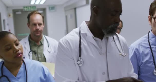 一组又一组的男医生和女医生在医院走廊里用平板电脑和说话 保健和保健服务 — 图库视频影像