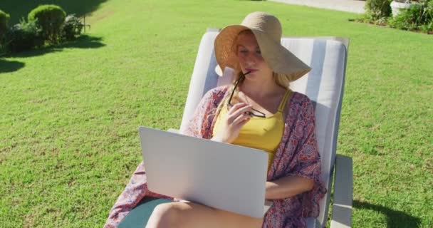 Vit Kvinna Som Använder Laptop När Hon Solar Solstol Trädgården — Stockvideo
