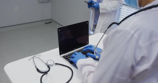 Midsektion Läkare Bär Ansiktsmask Och Kirurgiska Handskar Med Hjälp Laptop — Stockvideo