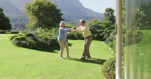 明るい晴れた日に庭で一緒に踊る幸せな白人のシニアカップル 定年退職したシニアカップルのライフスタイルのコンセプト — ストック動画
