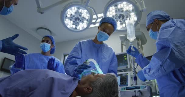 Змішані Гоночні Хірурги Носять Захисний Одяг Ставить Пацієнта Спати Операційному — стокове відео