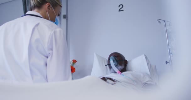 Diverse Doctor Wearing Face Mask Sitting Hospital Bed Patient Wearing — Vídeos de Stock