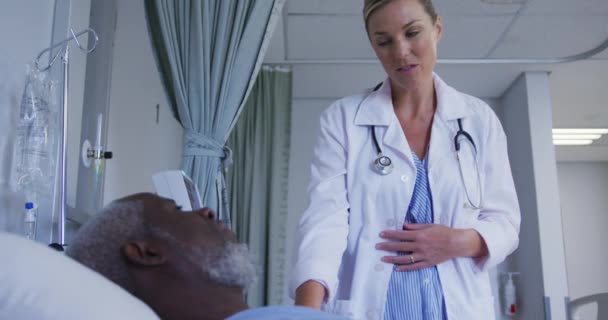 与非洲裔美国老年男性医生交谈的白人女医生躺在医院的床上 保健和医疗概念 — 图库视频影像
