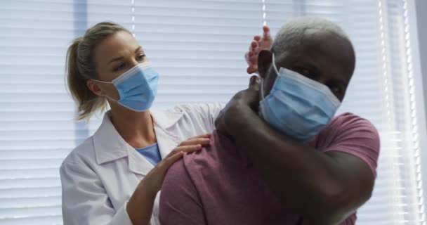 Zróżnicowany Lekarz Ortopeda Badający Pacjenta Maskach Medycyna Zdrowie Opieka Zdrowotna — Wideo stockowe