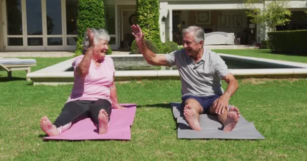 幸せな白人の高齢者のカップルは 太陽の下で高い5の庭でヨガを練習します 隔離中に隔離された家で — ストック動画