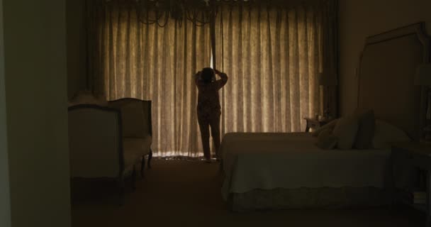 自宅で窓カーテンを開く白人のシニア女性の背面図 定年退職者のライフスタイルコンセプト — ストック動画