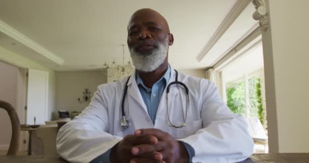 アフリカ系アメリカ人のシニア男性医師の自宅でカメラを見て話を肖像画 遠隔コミュニケーションと遠隔医療相談の概念 — ストック動画