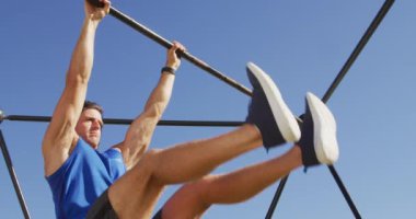 Beyaz adam dışarıda egzersiz yapıyor, tırmanma iskeletinde bacak kaldırıyor. Spor sahasında spor eğitimi için çapraz eğitim. 
