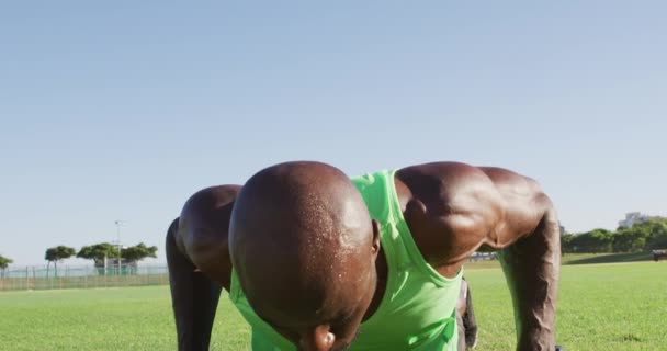厌倦了的非洲裔美国人在户外锻炼 做俯卧撑和吊起哑铃 在运动场上为健身进行交叉训练 — 图库视频影像