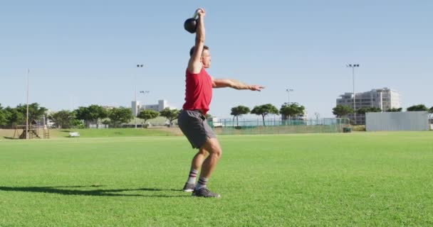 Fit Caucasian Man Exercising Outdoors Squatting Lifting Kettlebell Weight One — Video Stock